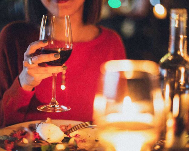 Woman sitting at a table holding a wine glass